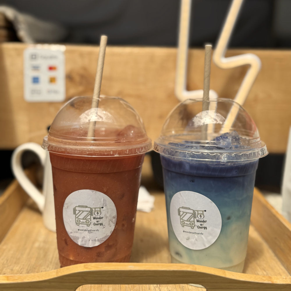 Two colorful iced drinks from Wonder with Energy with branded stickers, one red and one blue/white, on a wooden tray.